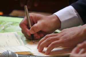 Mãos assinam documento formal sobre escrivaninha — formalização de negócio jurídico