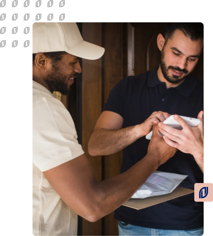 Homem branco de cabelo preto e barba assinando um tablet segurado por um homem negro de cabelo preto e barba. Ambos estão sorrindo.